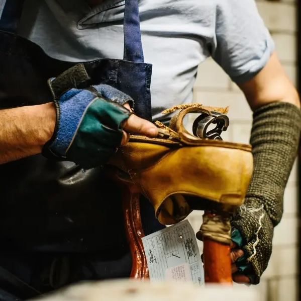 Hands working on leather footwear at a bench